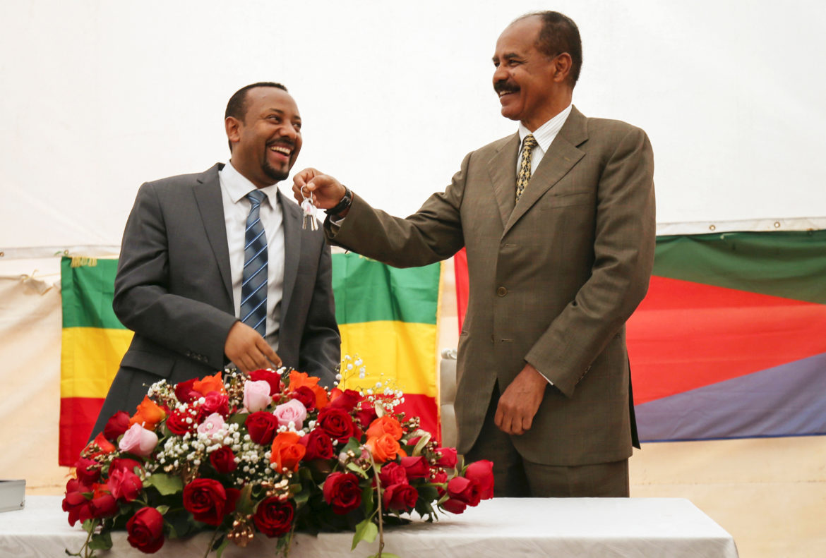 Abiy Ahmed til venstre og Isaias Afwerki til høyre. Begge smiler. Afwerki holder opp et nøkkelknippe.