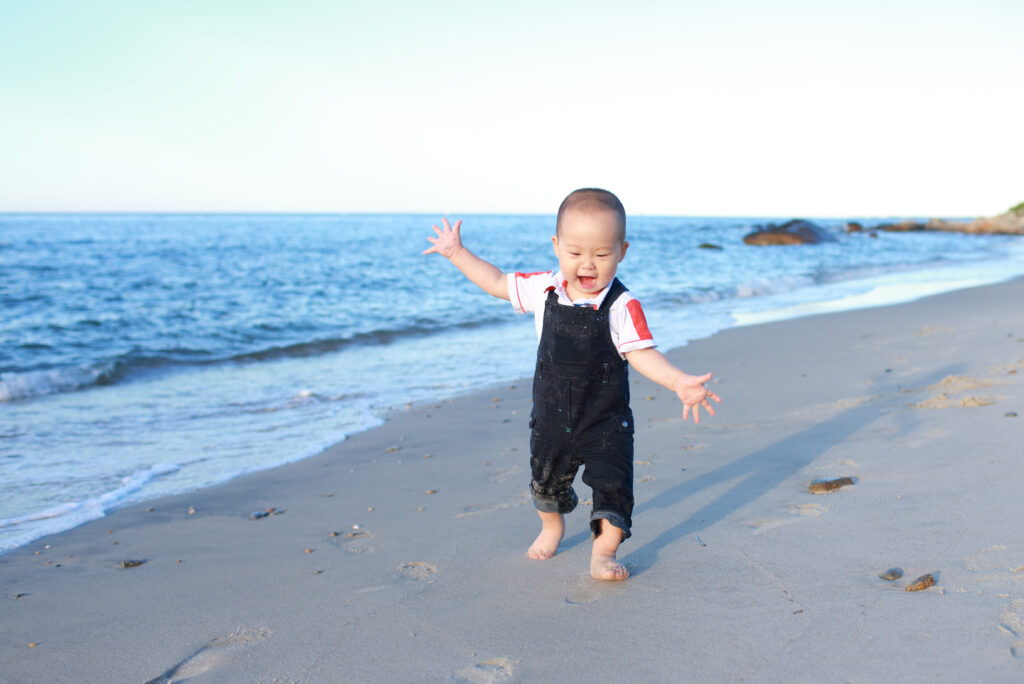 Ettåring i skitten snekkerbukse løper på strand visualiserer diktet «Reise seg» av Marie Takvam.