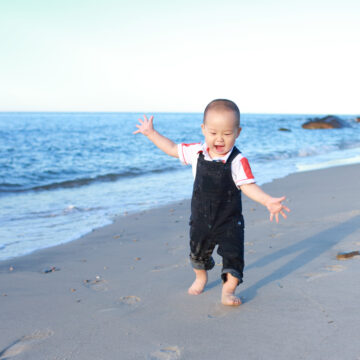 Ettåring i skitten snekkerbukse løper på strand visualiserer diktet «Reise seg» av Marie Takvam.