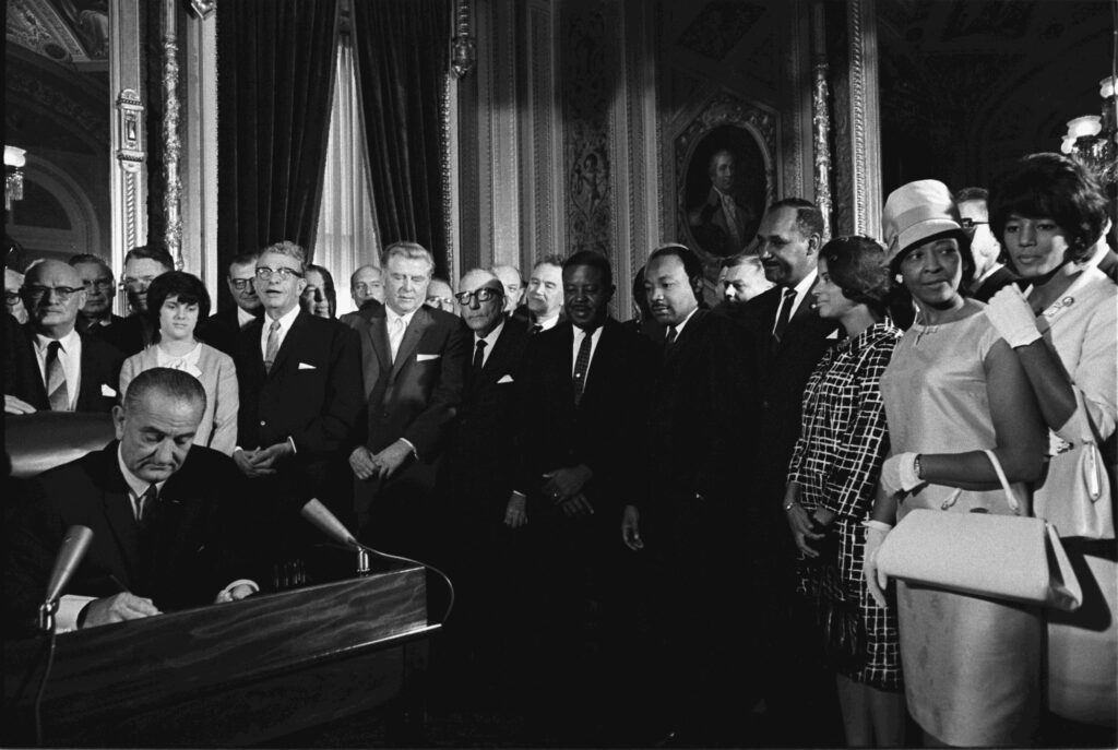 President Lyndon B. Johnson signerer Valgloven av 1965. Flere står rundt og ser på, blant annet Martin Luther King jr.