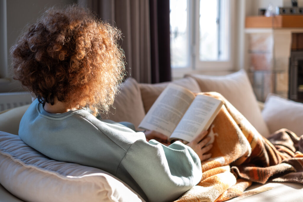 Ungdom som leser samisk roman på sofaen