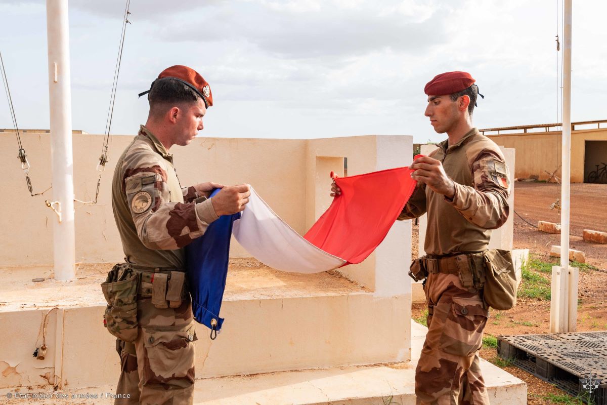 To franske soldater har firt ned det franske flagget. De står med det mellom seg og skal pakke det sammen. 