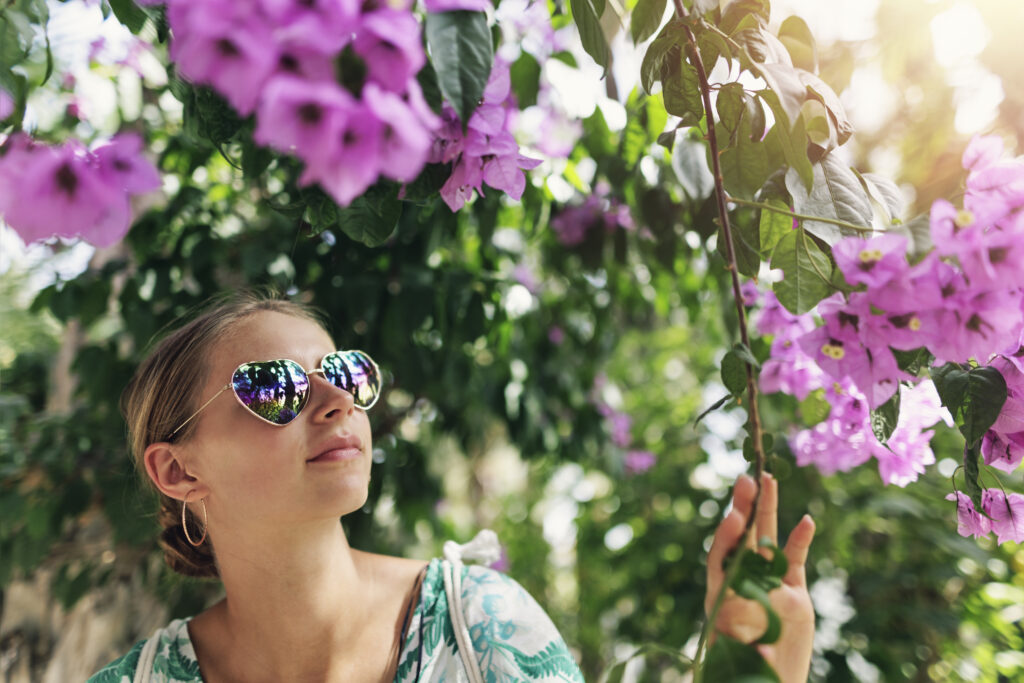 Tenåringsjente med solbriller ser på blomstrende trær