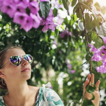 Tenåringsjente med solbriller ser på blomstrende trær